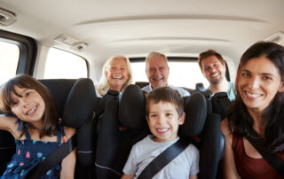 Large multi-generational family sitting comfortably in a 3-row SUV with kids in booster seats.